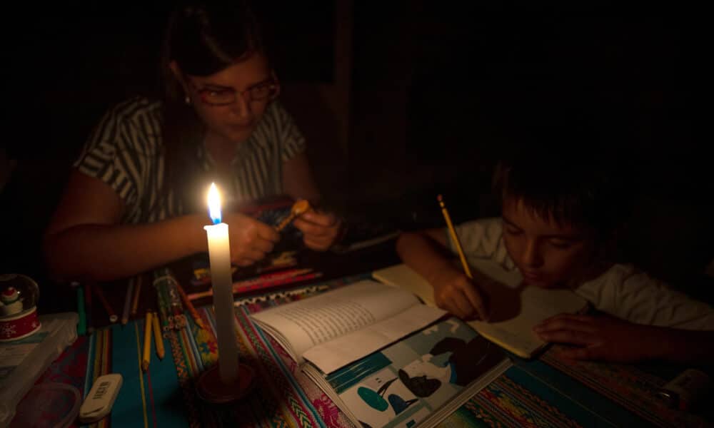 Fotografía de archivo en donde una madre y su hijo estudian a la luz de la vela en Quito (Ecuador). EFE/José Jácome