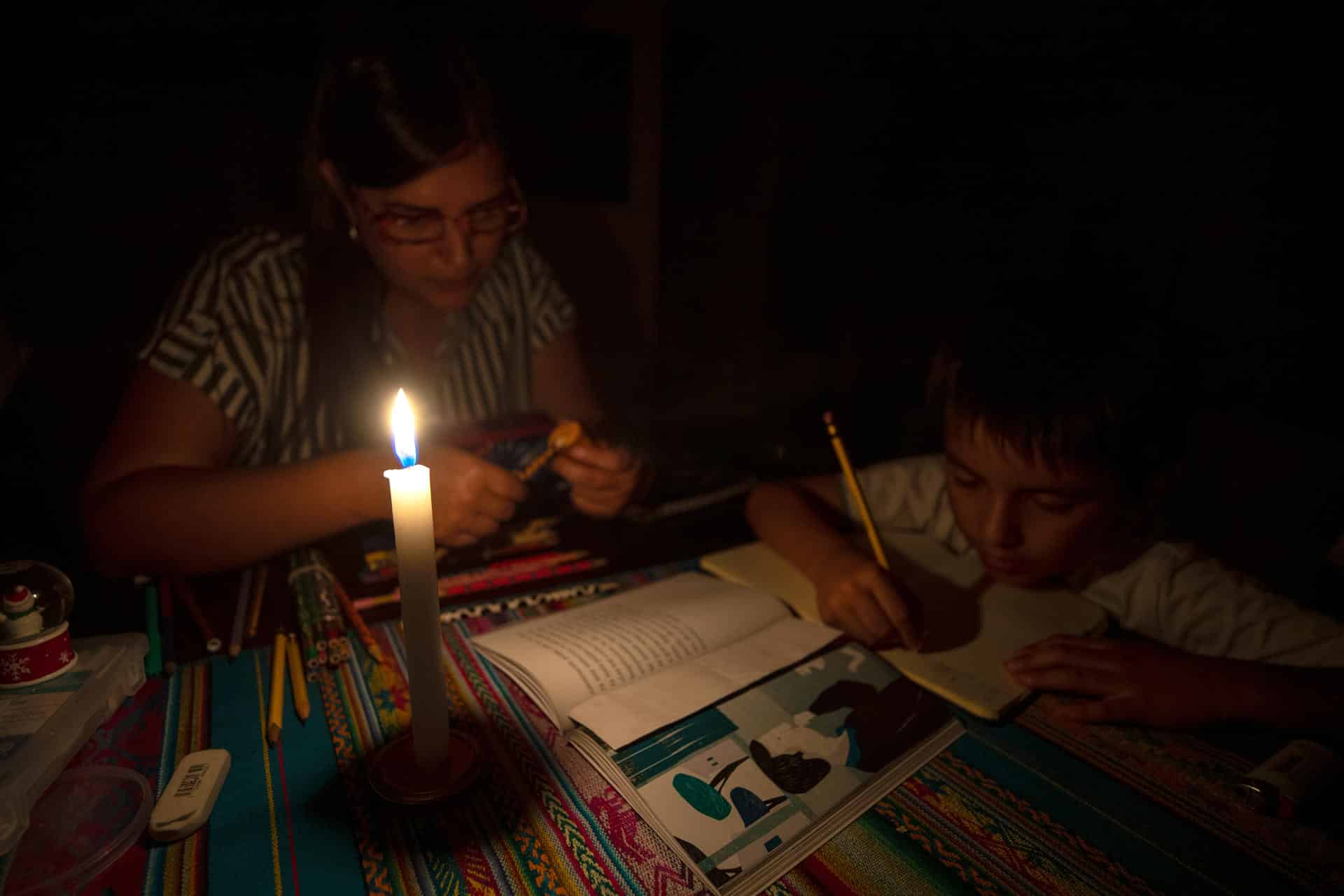 Fotografía de archivo en donde una madre y su hijo estudian a la luz de la vela en Quito (Ecuador). EFE/José Jácome