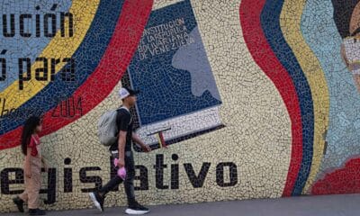 Un hombre camina frente a un mural con la imagen de un libro de la Constitución venezolana, en Caracas (Venezuela). EFE/ Ronald Peña R.