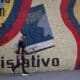 Un hombre camina frente a un mural con la imagen de un libro de la Constitución venezolana, en Caracas (Venezuela). EFE/ Ronald Peña R.