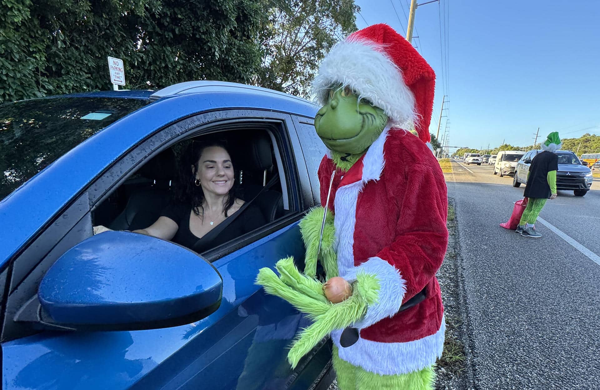 Fotografía cedida por la Oficina de Noticias de los Cayos de Florida donde aparece el coronel Lou Caputo, de la Oficina del Alguacil del Condado de Monroe, disfrazado de 'Grinch', el malvado duende verde navideño, ofreciendo una cebolla a una conductora que iba ligeramente con exceso de velocidad en una zona escolar este jueves en Cayo Largo, Florida (EE.UU.). EFE/Andy Newman/Oficina de Noticias de los Cayos de Florida /SOLO USO EDITORIAL /NO VENTAS /SOLO DISPONIBLE PARA ILUSTRAR LA NOTICIA QUE ACOMPAÑA /CRÉDITO OBLIGATORIO