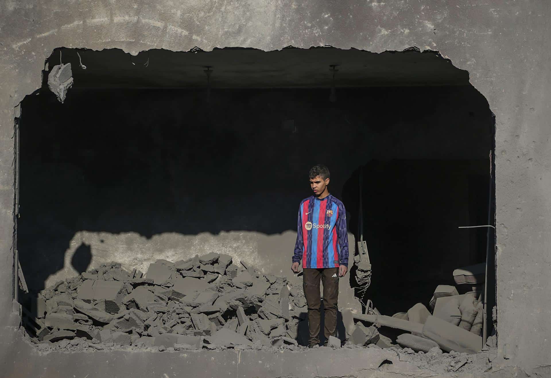 Un joven palestino permanece de pie entre los escombros de su casa, destruida por un ataque aéreo israelí sobre el campo de refugiados de Al Nuseirat (Gaza). EFE/ Mohammed Saber