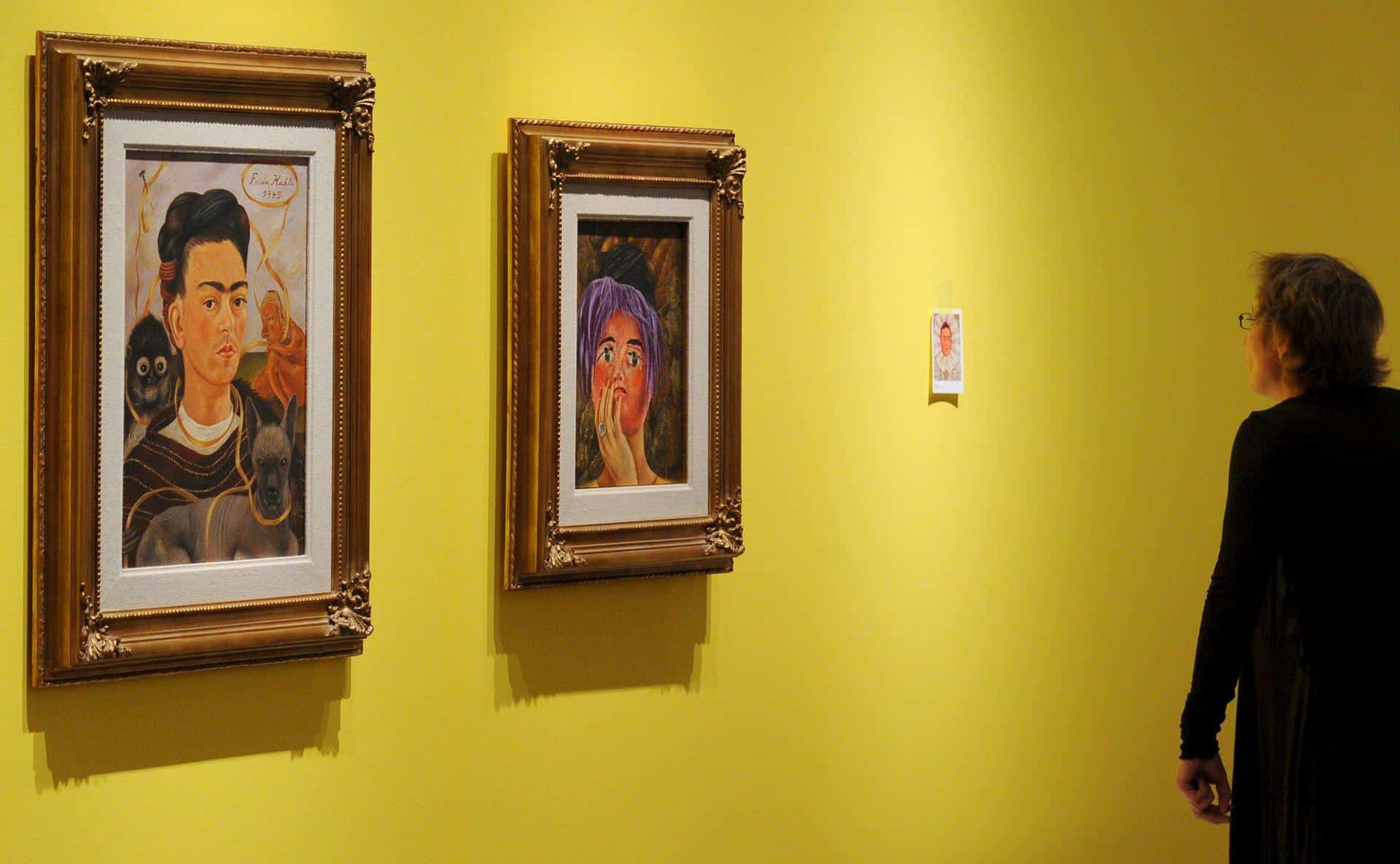 Fotografía de archivo en donde una mujer contempla los cuadros 'Autorretrato con Changuito' (1941), (i), y 'La Máscara' (1945), (d), de la pintora mexicana Frida Khalo. EFE/Jens Kalaene