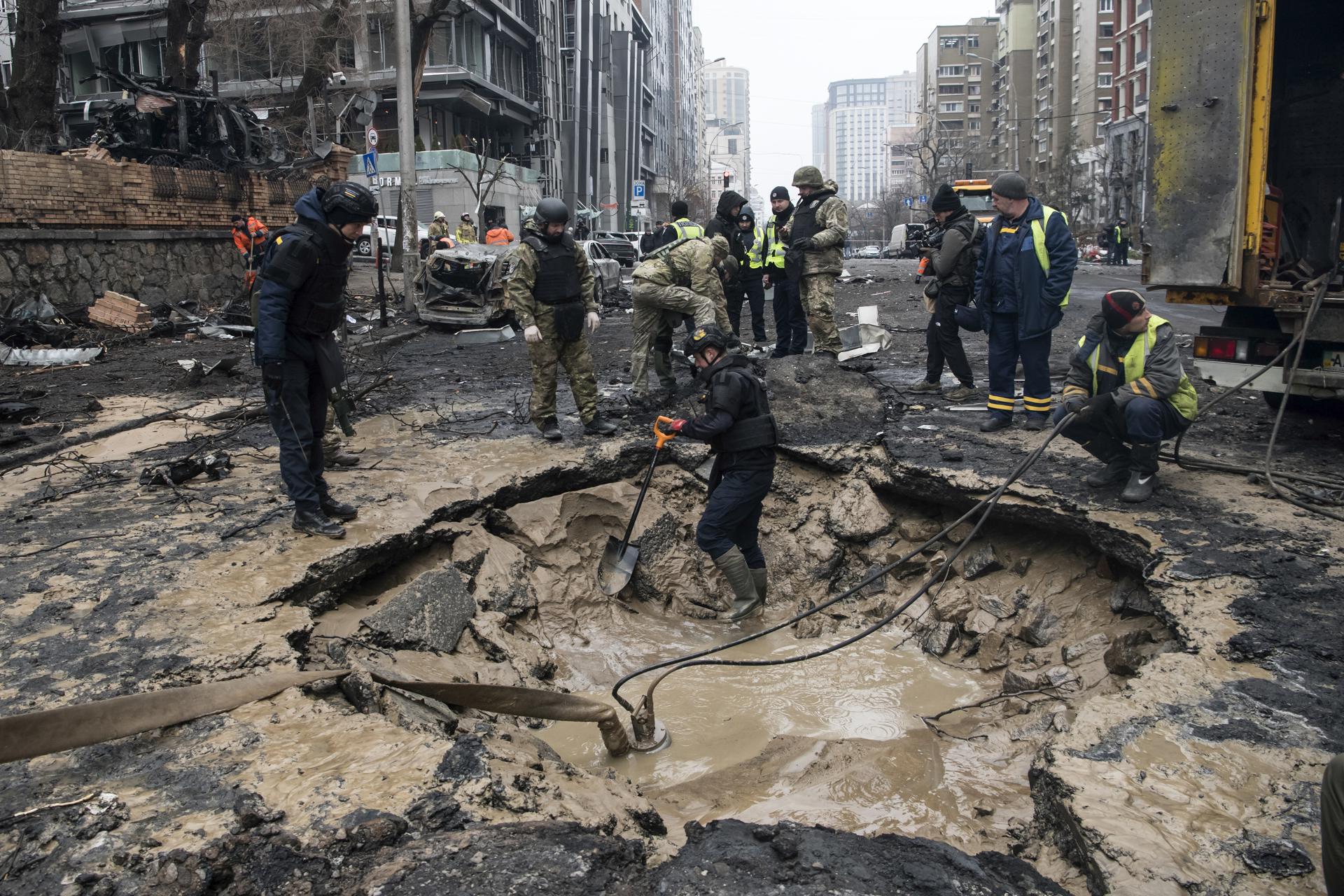 Trabajadores comunitarios drenan el agua de un cráter de explosión mientras expertos y policías trabajan en el lugar de un ataque con misiles en el centro de Kyiv, Ucrania, 20 de diciembre de 2024, en medio de la invasión rusa. Al menos una persona murió y otras 10 resultaron heridas como resultado del bombardeo ruso en Kyiv, según el Servicio Estatal de Emergencia de Ucrania (SESU). (Rusia, Ucrania, Kiev) EFE/EPA/MAXYM MARUSENKO