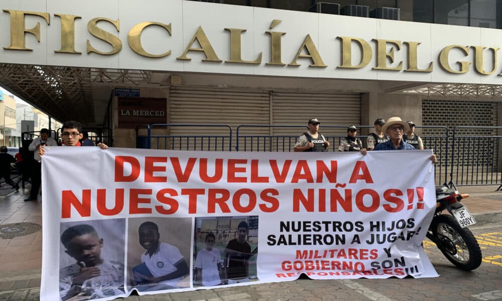 Luis Arroyo (d) y Josué Arroyo (i), padre y hermano de un menor desaparecido, sostienen un cartel con la foto de sus familiares en los exteriores de la Fiscalía Provincial del Guayas en Guayaquil (Ecuador). EFE/Cristina Bazán