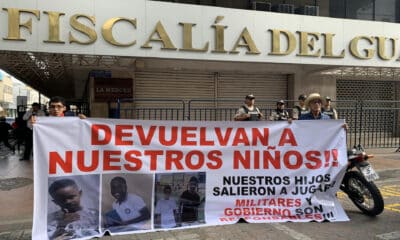 Luis Arroyo (d) y Josué Arroyo (i), padre y hermano de un menor desaparecido, sostienen un cartel con la foto de sus familiares en los exteriores de la Fiscalía Provincial del Guayas en Guayaquil (Ecuador). EFE/Cristina Bazán