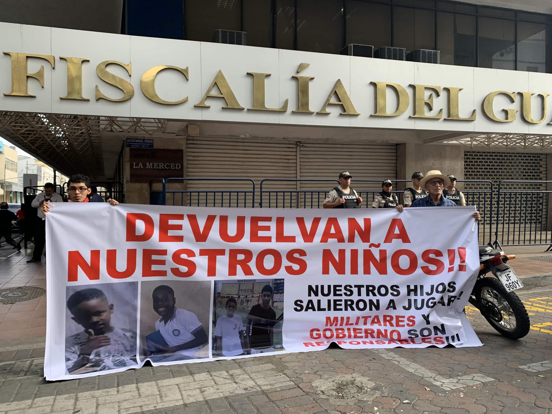 Luis Arroyo (d) y Josué Arroyo (i), padre y hermano de un menor desaparecido, sostienen un cartel con la foto de sus familiares en los exteriores de la Fiscalía Provincial del Guayas en Guayaquil (Ecuador). EFE/Cristina Bazán