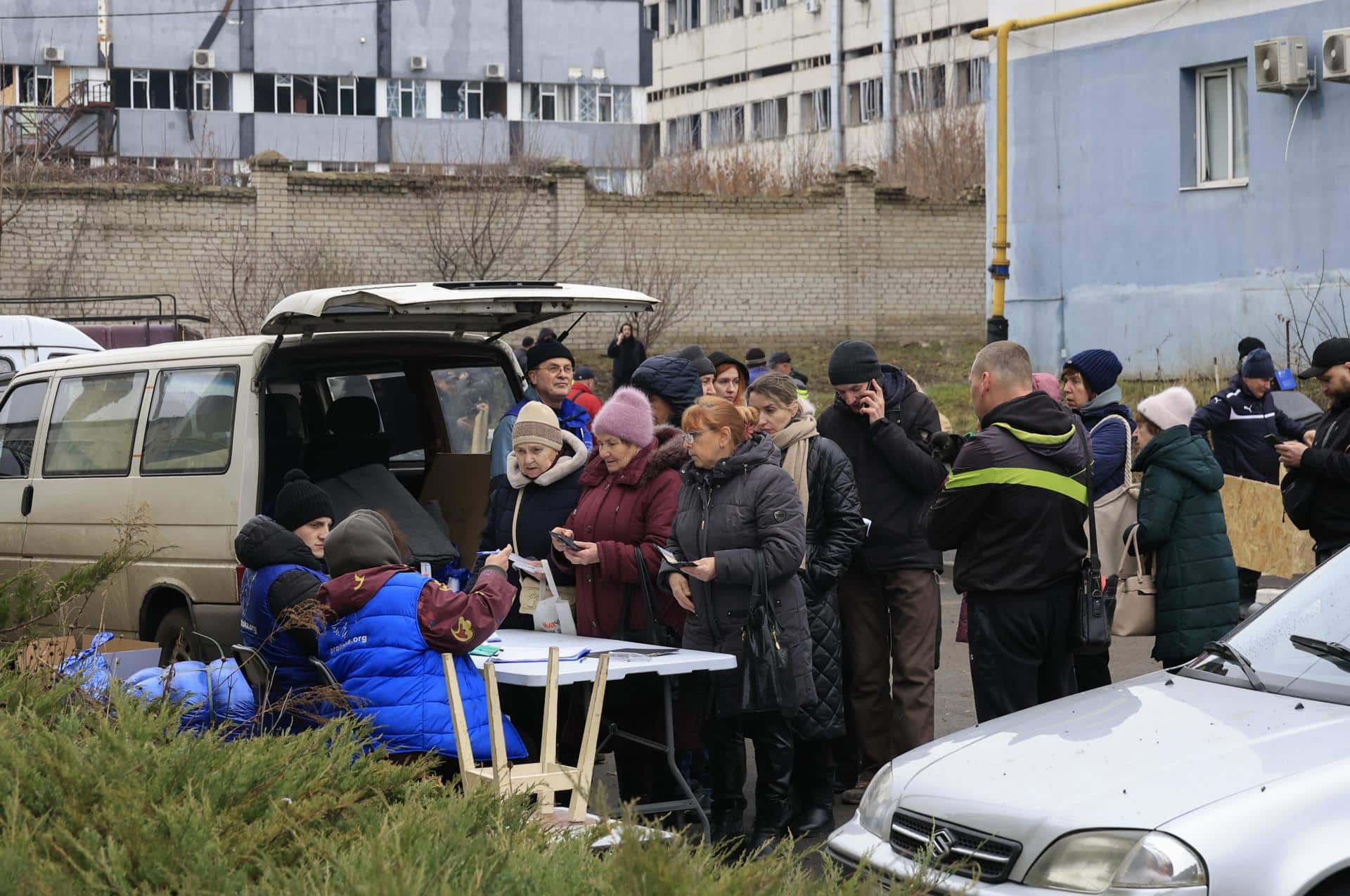 Jarkov (Ucrania), 25/12/2024.- Un grupo de personas hacen cola para recibir ayuda junto a un edificio de viviendas dañado por un ataque con un misil ruso en la ciudad ucraniana de Jarkov. EFE/EPA/SERGEY KOZLOV