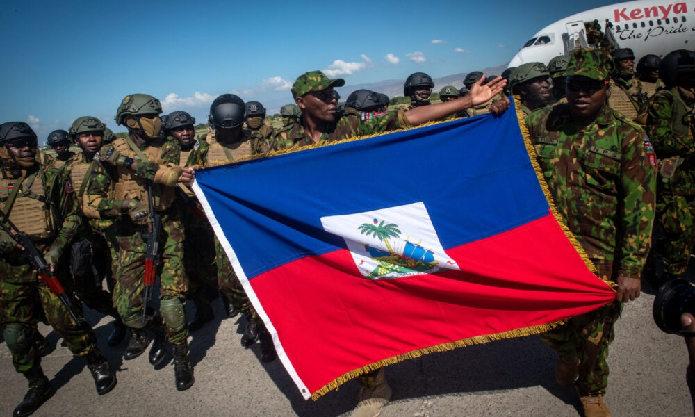 Policías kenianos sostienen una bandera de Haití a su llegada al aeropuerto internacional Toussaint Louverture este sábado, en Puerto Príncipe (Haití). EFE/ Johnson Sabin