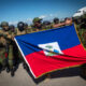 Policías kenianos sostienen una bandera de Haití a su llegada al aeropuerto internacional Toussaint Louverture este sábado, en Puerto Príncipe (Haití). EFE/ Johnson Sabin