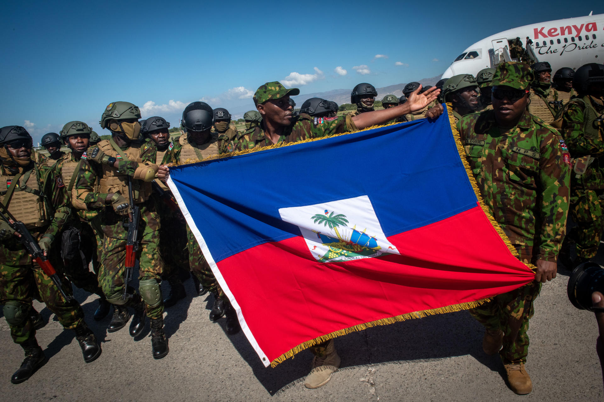 Policías kenianos sostienen una bandera de Haití a su llegada al aeropuerto internacional Toussaint Louverture este sábado, en Puerto Príncipe (Haití). EFE/ Johnson Sabin