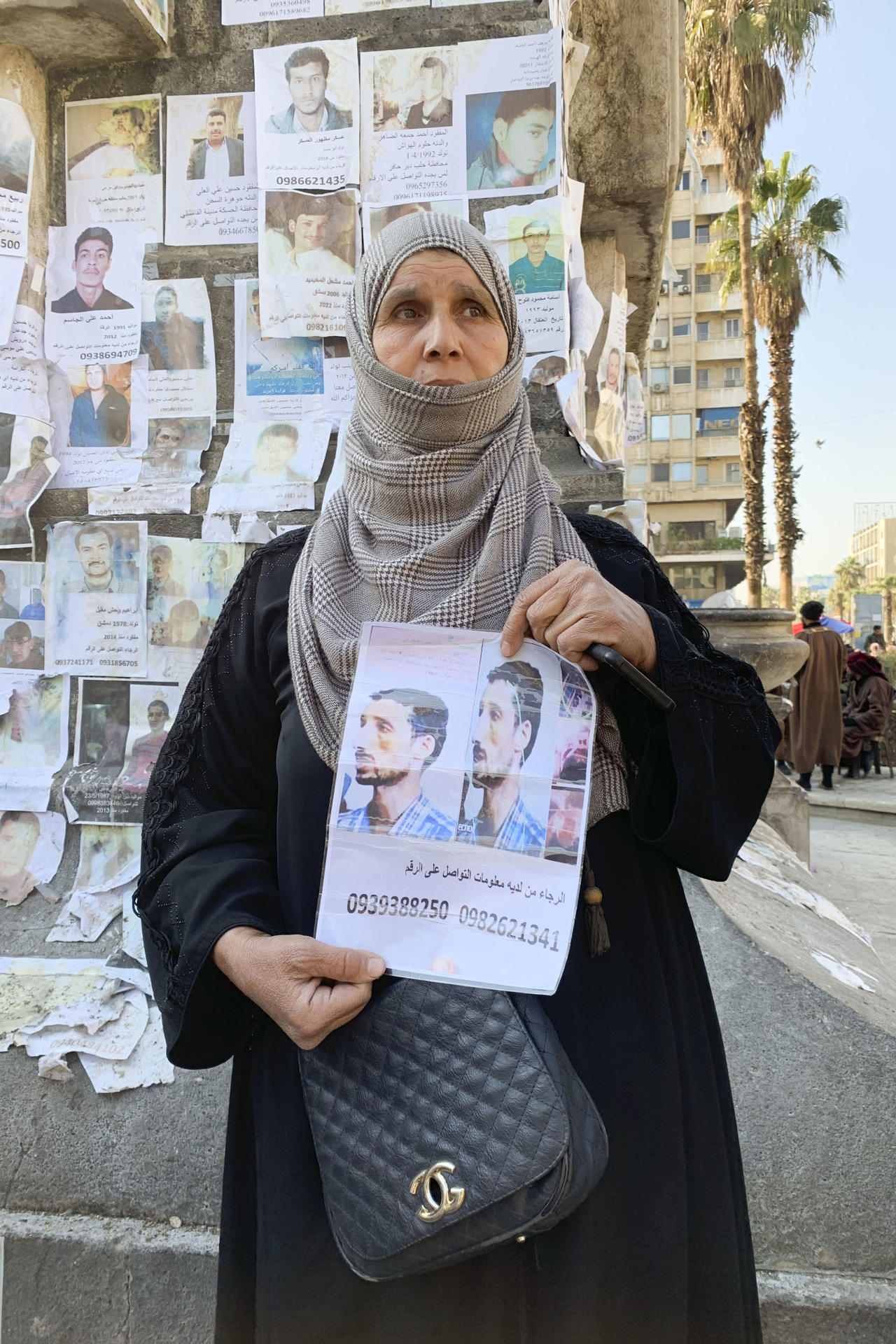 La madre de un desaparecido muestra una foto de su hijo, aún en paradero desconocido un mes después del derrocamiento del régimen sirio, este 7 de enero de 2025 en Damasco. Ya ha pasado un mes desde que el derrocamiento de Bachar al Asad permitiera a miles de familias reencontrarse con sus seres queridos desaparecidos durante años en Siria, pero Samah (nombre ficticio) acaba de llegar a una plaza de Damasco para pegar un cartel con la cara de su hijo y un teléfono de contacto. 
EFE/ Noemí Jabois