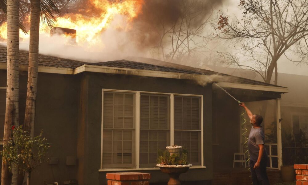 Un hombre utiliza una manguera de jardín para apagar las llamas en el tejado de una casa que arde como consecuencia del incendio forestal Eaton en Altadena, California (EE.UU.). EFE/CAROLINE BREHMAN