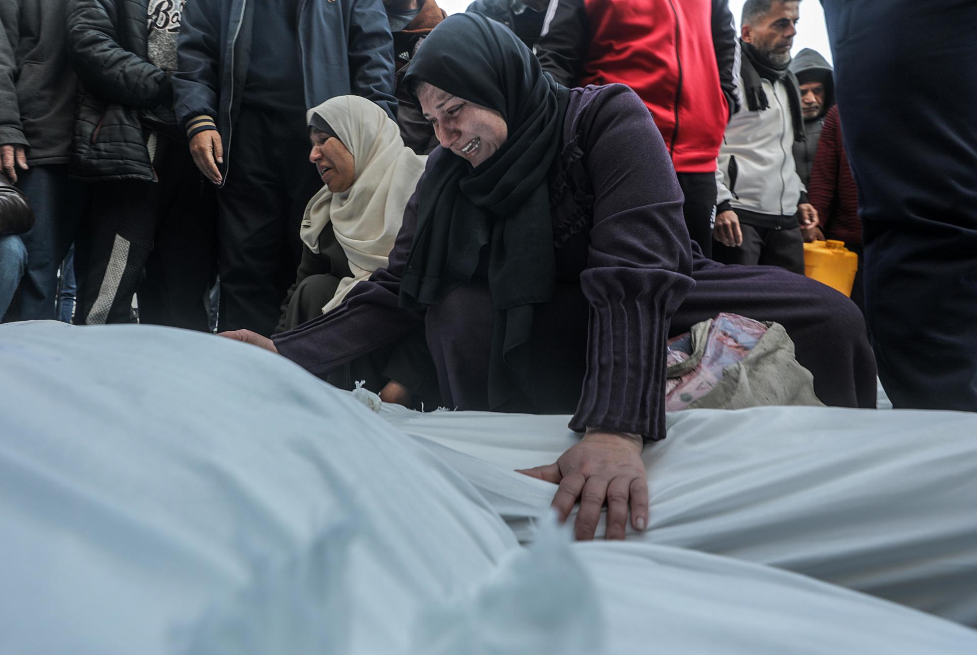 Una mujer palestina llora sobre los cuerpos cubiertos de los miembros de una familia palestina asesinados en un ataque aéreo israelí, en el Hospital de los Mártires de Al Aqsa en la ciudad de Deir Al Balah, en el centro de la Franja de Gaza, 15 de enero de 2025. 
 EFE/EPA/MOHAMMED SABER