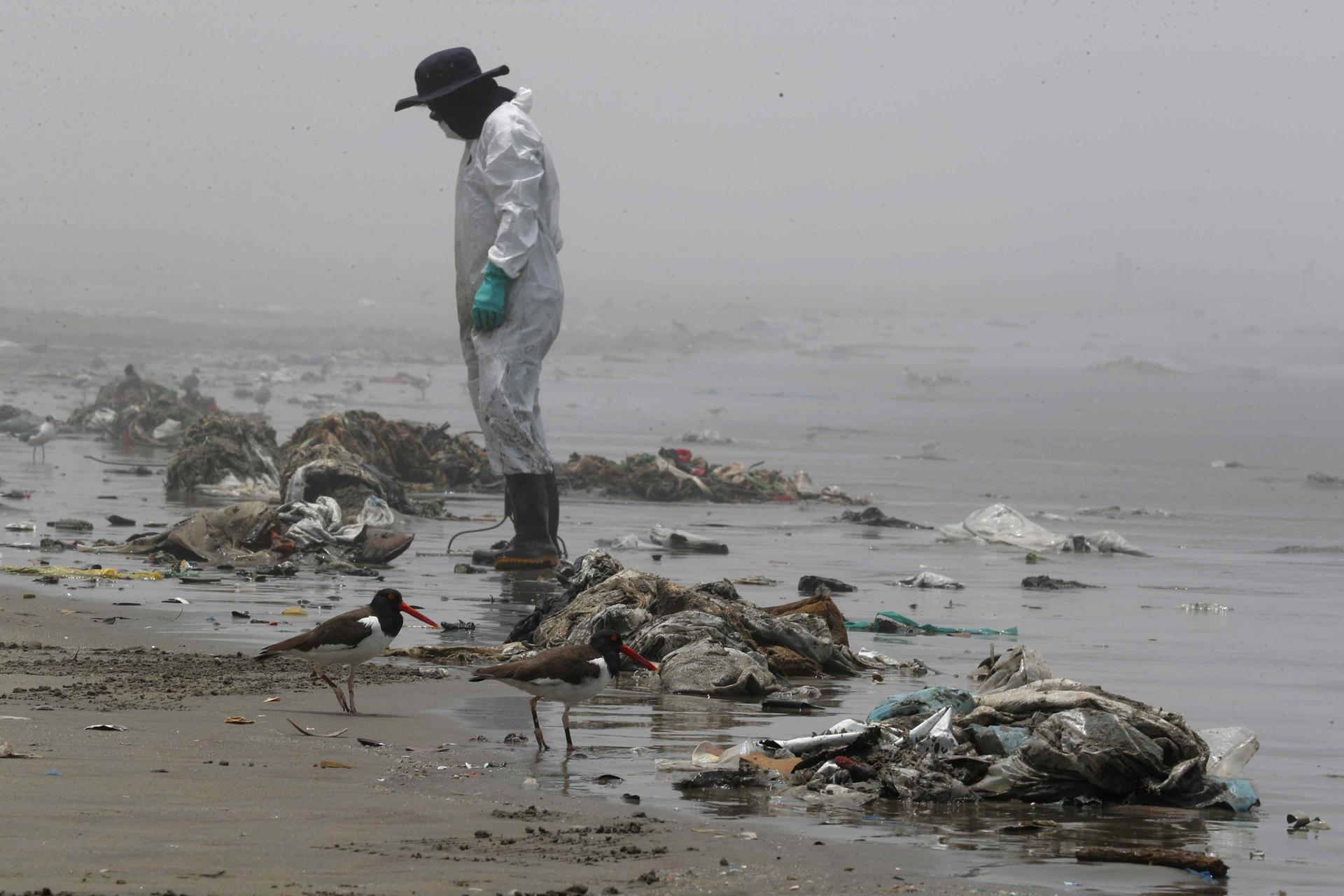 Fotografía de archivo de personal de limpieza en la playa Cavero tras el desastre ambiental que sufrieron las costas de Lima por el derrame de crudo en la refinería La Pampilla. EFE/Paolo Aguilar