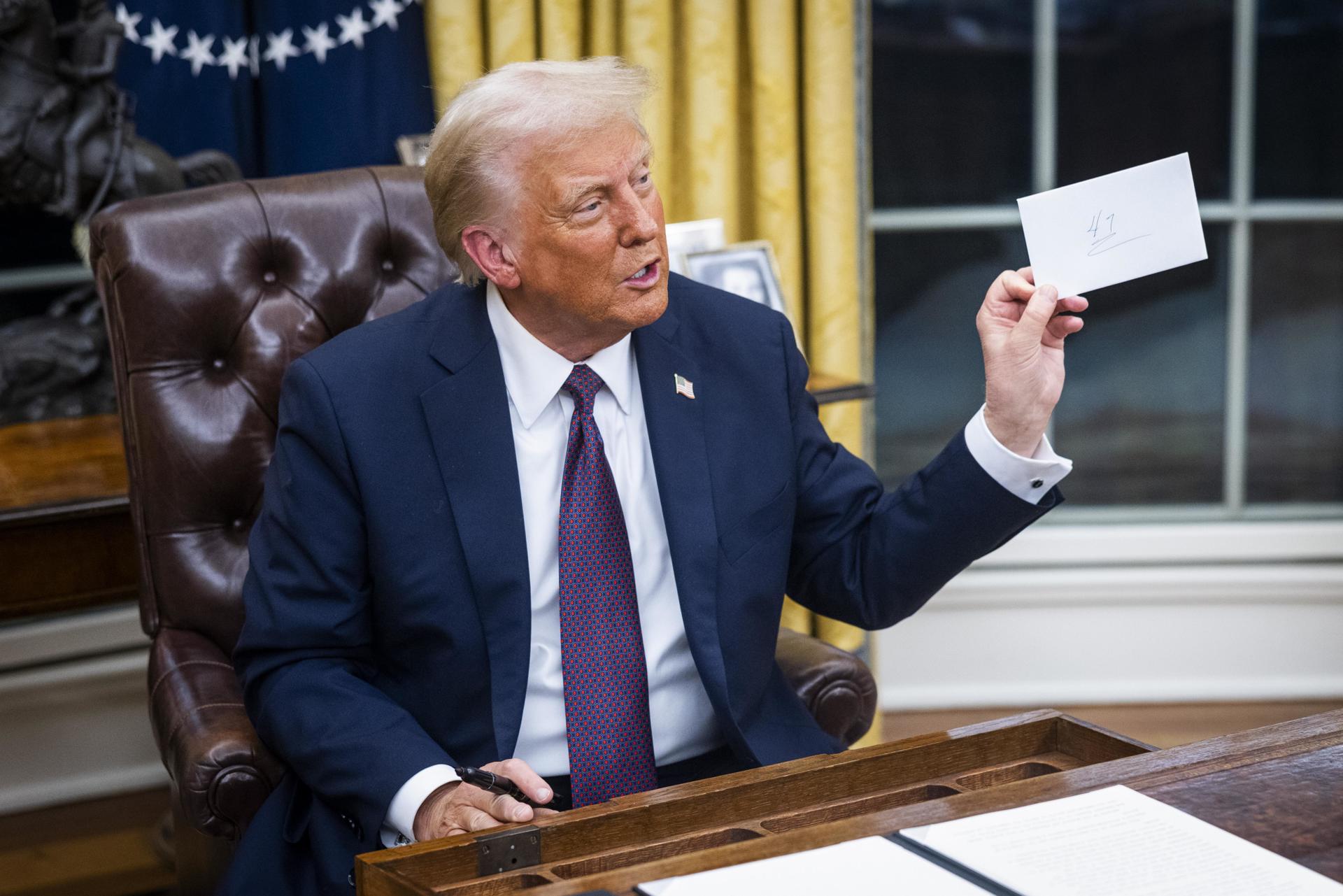 El presidente Donald Trump sostiene una carta que le dejó el expresidente Joe Biden en el cajón del escritorio Resolute el primer día de su presidencia en la Oficina Oval de la Casa Blanca en Washington, DC (EE.UU.). EFE/JIM LO SCALZO / POOL