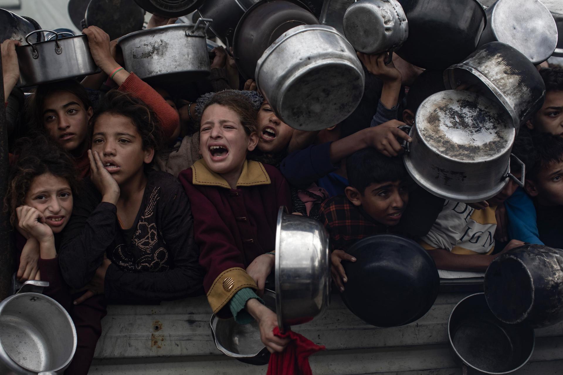 Niños palestinos sostienen ollas para recibir comida de una cocina benéfica en Jan Yunis, en el sur de la Franja de Gaza, el 29 de noviembre de 2024. EFE/EPA/HAITHAM IMAD