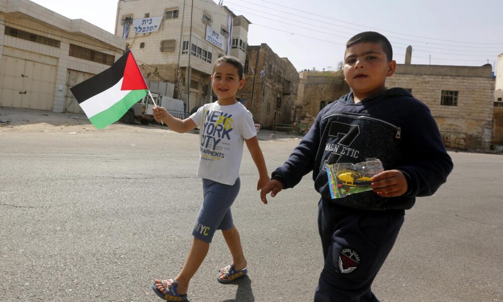 Foto de archivo de unos niños que muestran banderas palestinas en Hebrón, Cisjordania. EFE/ABED AL HASHLAMOUN