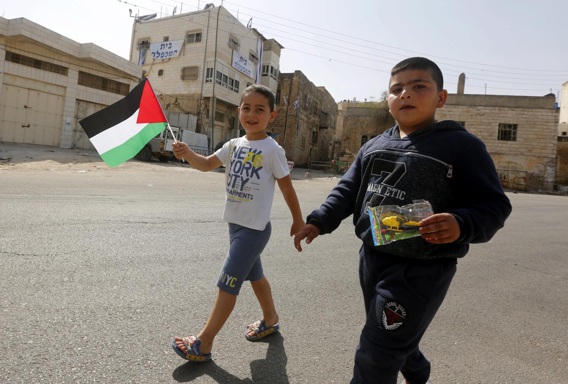 Foto de archivo de unos niños que muestran banderas palestinas en Hebrón, Cisjordania. EFE/ABED AL HASHLAMOUN