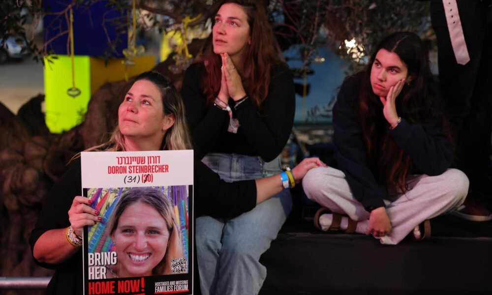 Frontera de Gaza (Israel) (EFE).- Varias personas observan una transmisión en vivo en una pantalla grande que informa sobre la liberación de tres rehenes israelíes, Romi Gonen, Emily Damari y Doron Steinbrecher, transferidos de Hamás a la Cruz Roja. EFE/EPA/ABIR SULTAN