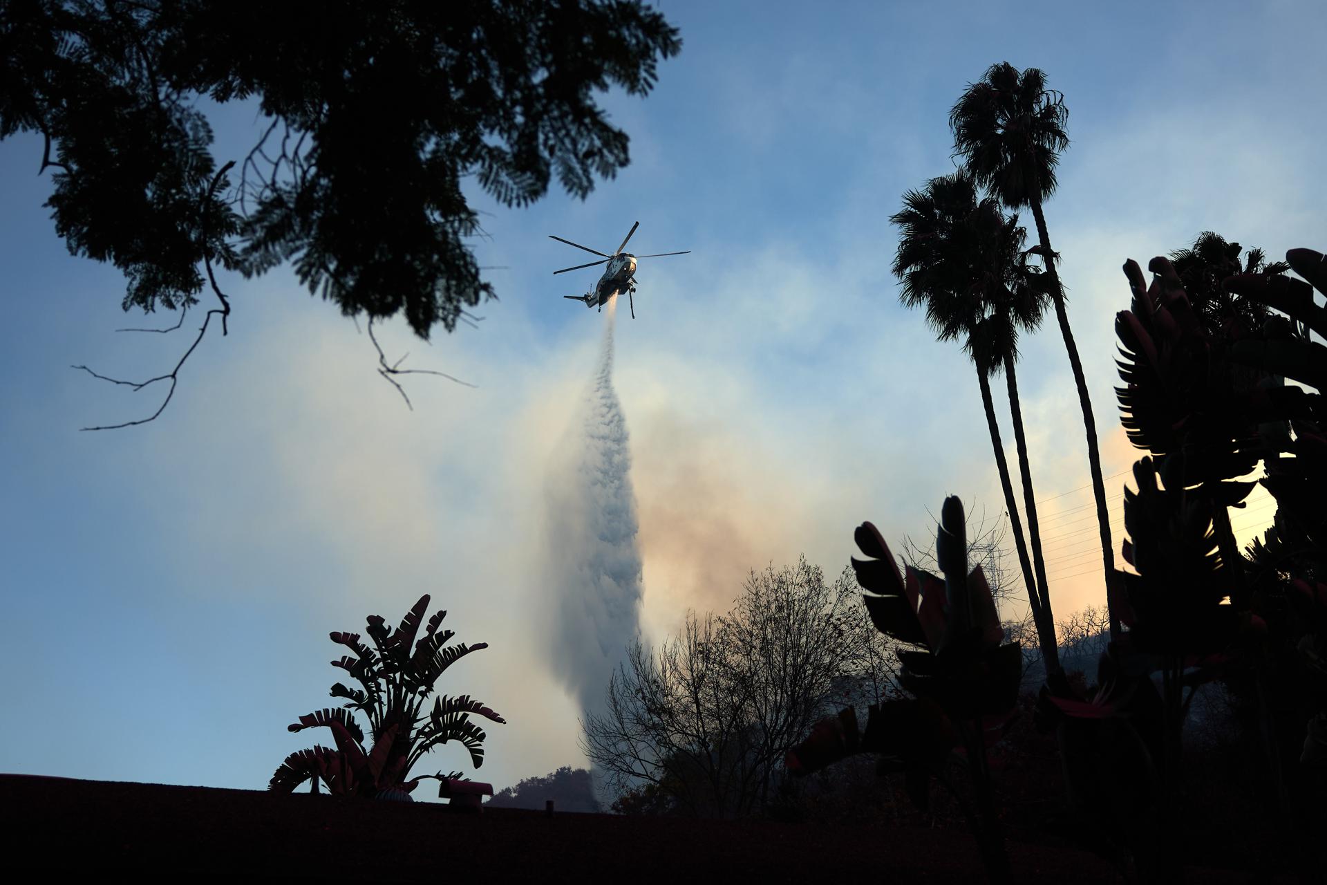 Un helicóptero lanza agua sobre el incendio forestal de Palisades, en Los Ángeles, California (EE.UU.). EFE/ALLISON DINNER