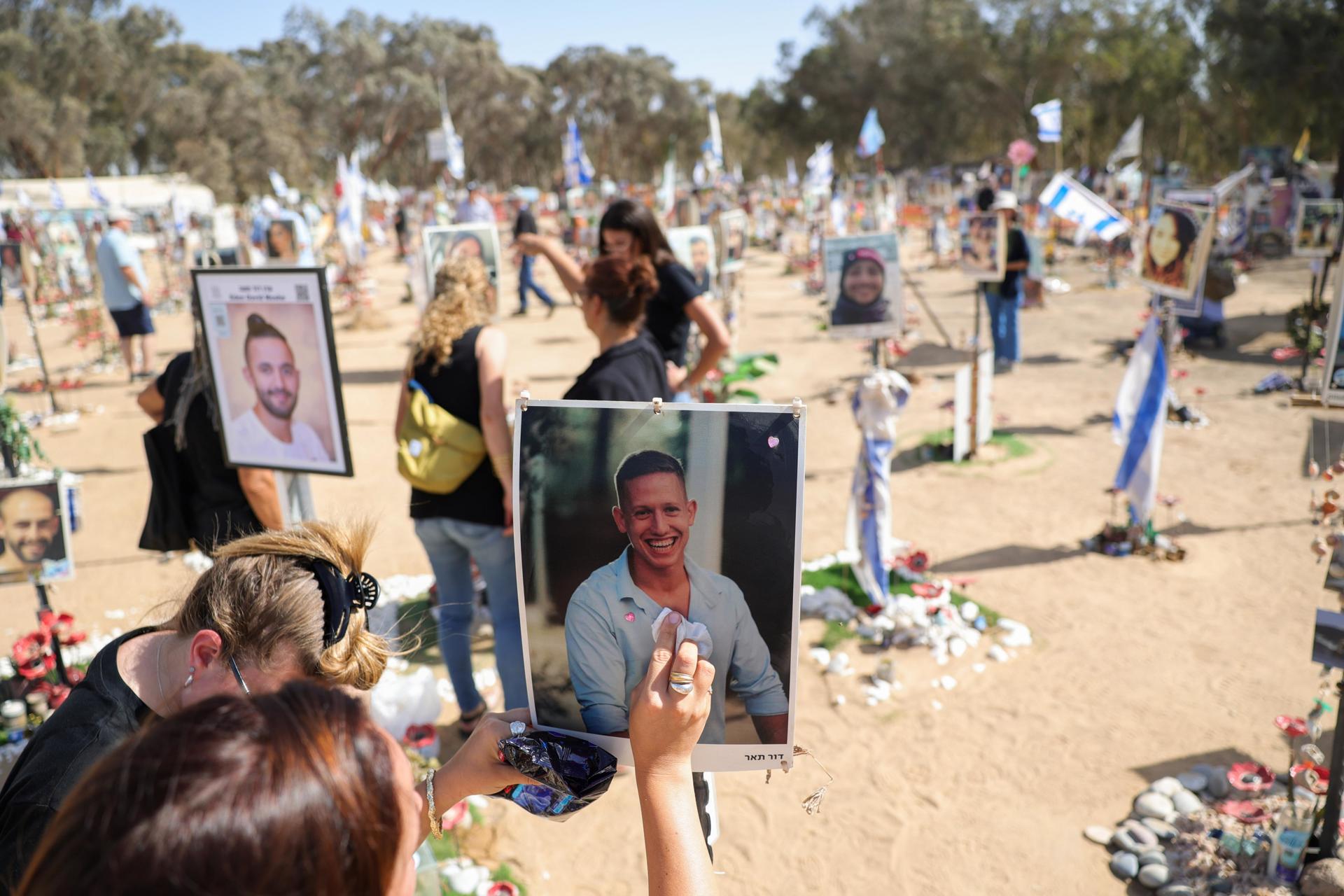 Una mujer limpia una foto de un familiar y memoriales para los asistentes israelíes al festival que fueron asesinados por Hamas en el lugar del rave del Supernova Music Festival cerca de Kibbutz Reim, Sur de Israel. EFE/ABIR SULTAN