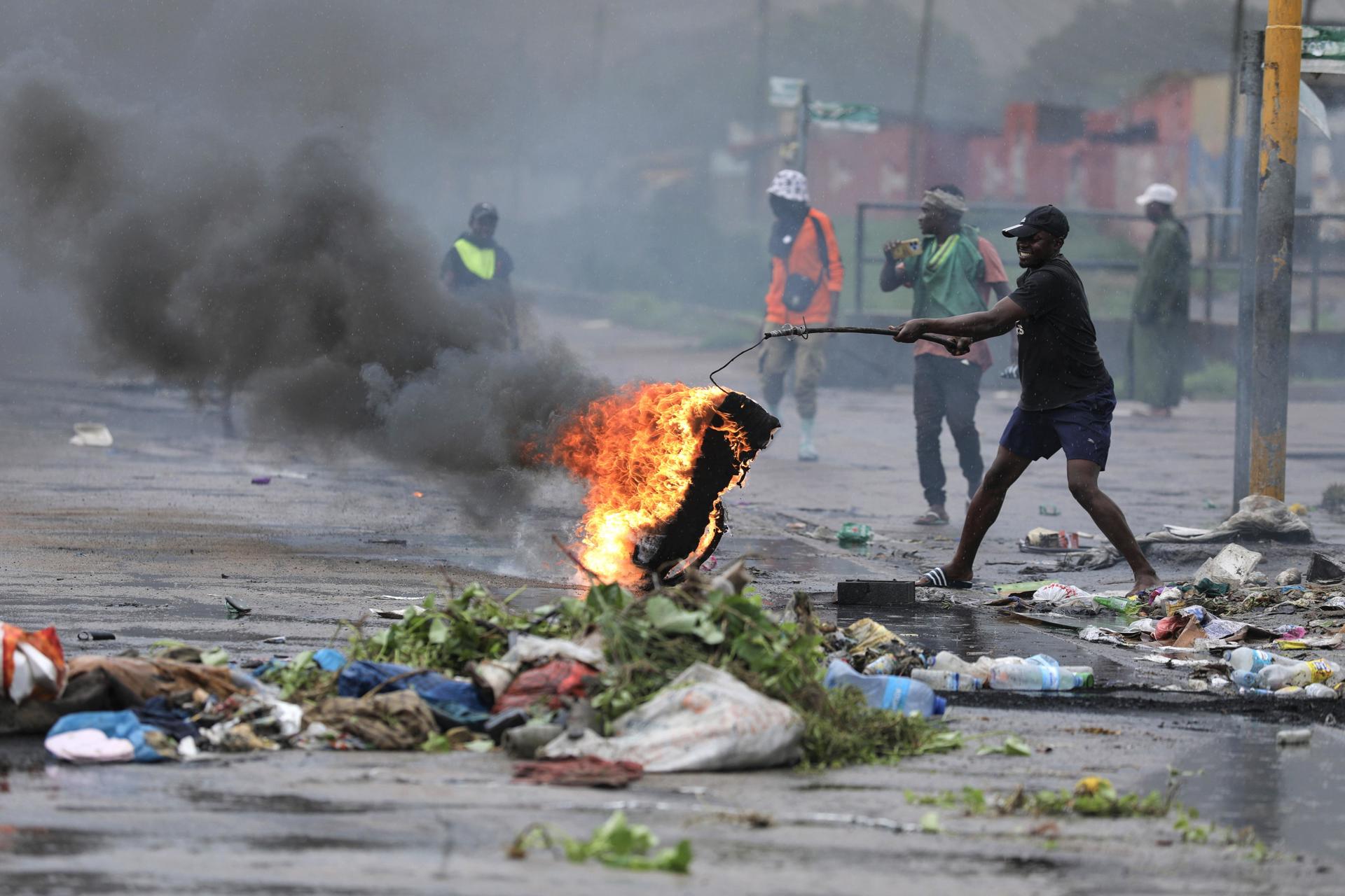 Un manifestante lleva un neumático en llamas durante una protesta en el día de la inauguración del nuevo parlamento, en Maputo, Mozambique, 13 de enero de 2025. La ceremonia de toma de posesión de los diputados elegidos para el nuevo parlamento de Mozambique, la Asamblea de la República, está en marcha mientras que dos partidos de oposición, Renamo y MDM, que rechazan el resultado de las elecciones de octubre de 2024, boicotearon la ceremonia. (Protests) EFE/EPA/LUISA NHANTUMBO