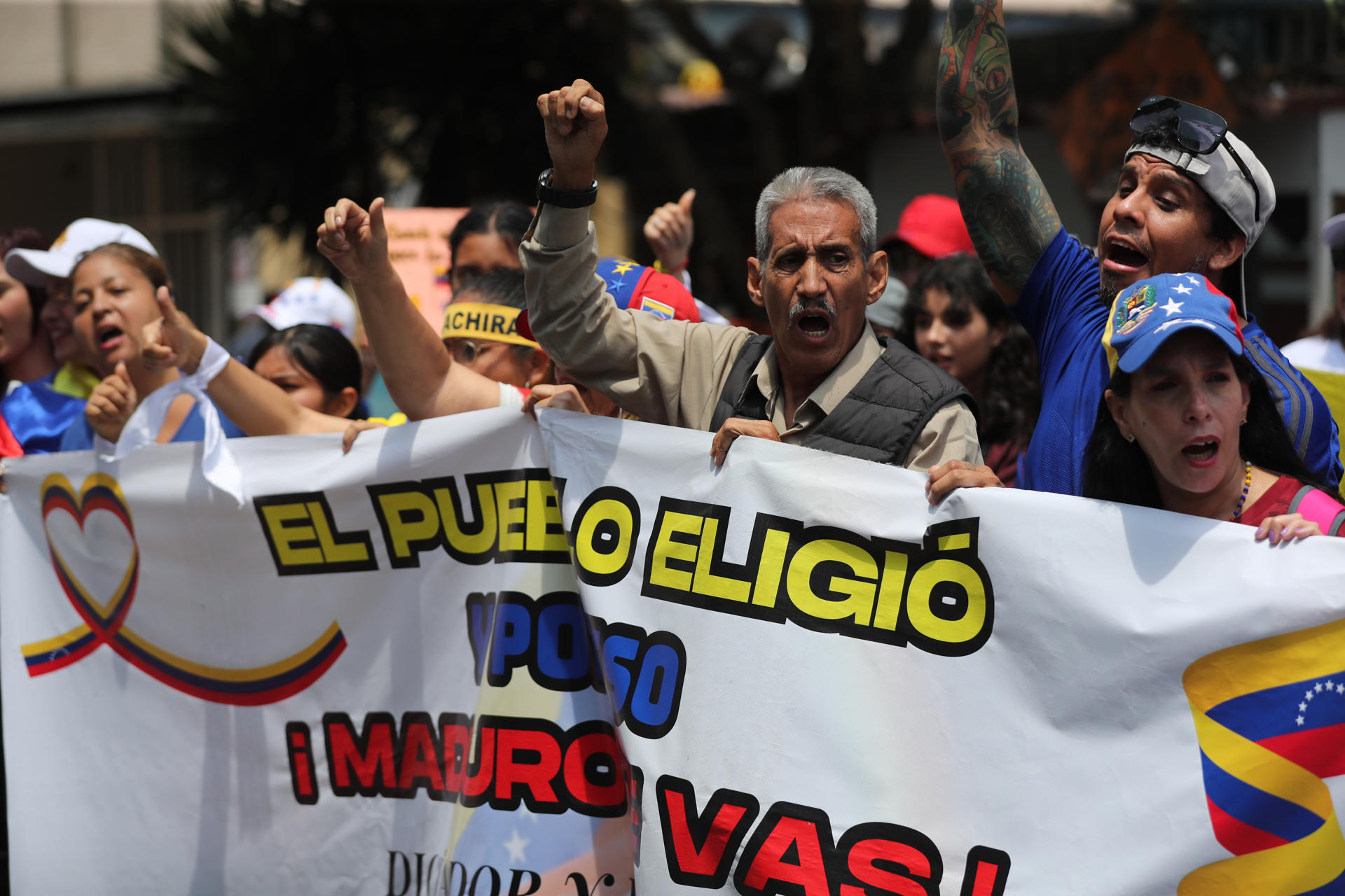 Personas se manifiestan con carteles afuera de la embajada de Venezuela este viernes en Lima (Perú), para seguir manifestando su apoyo al líder antichavista Edmundo González Urrutia. EFE/ Paolo Aguilar