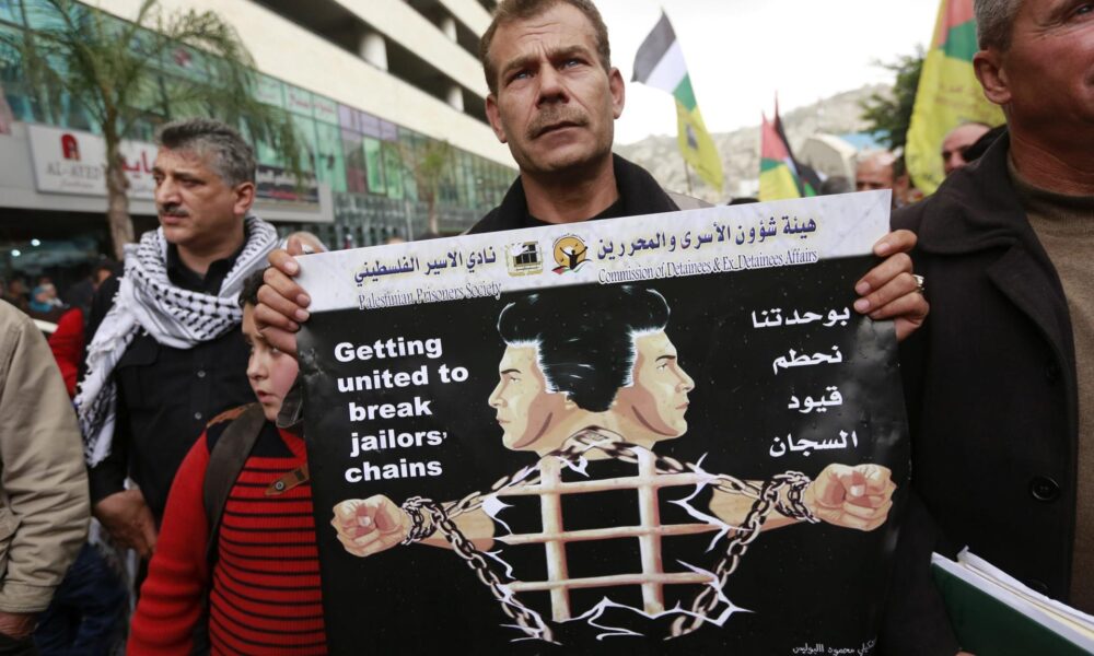 Imagen de archivo de un hombre palestino con un cartel en el que se lee "Unidos para romper las cadenas de la cárcel" durante una protesta para pedir la liberación de sus familiares encarcelados en centros penitenciarios israelíes. EFE/Alaa Badarneh