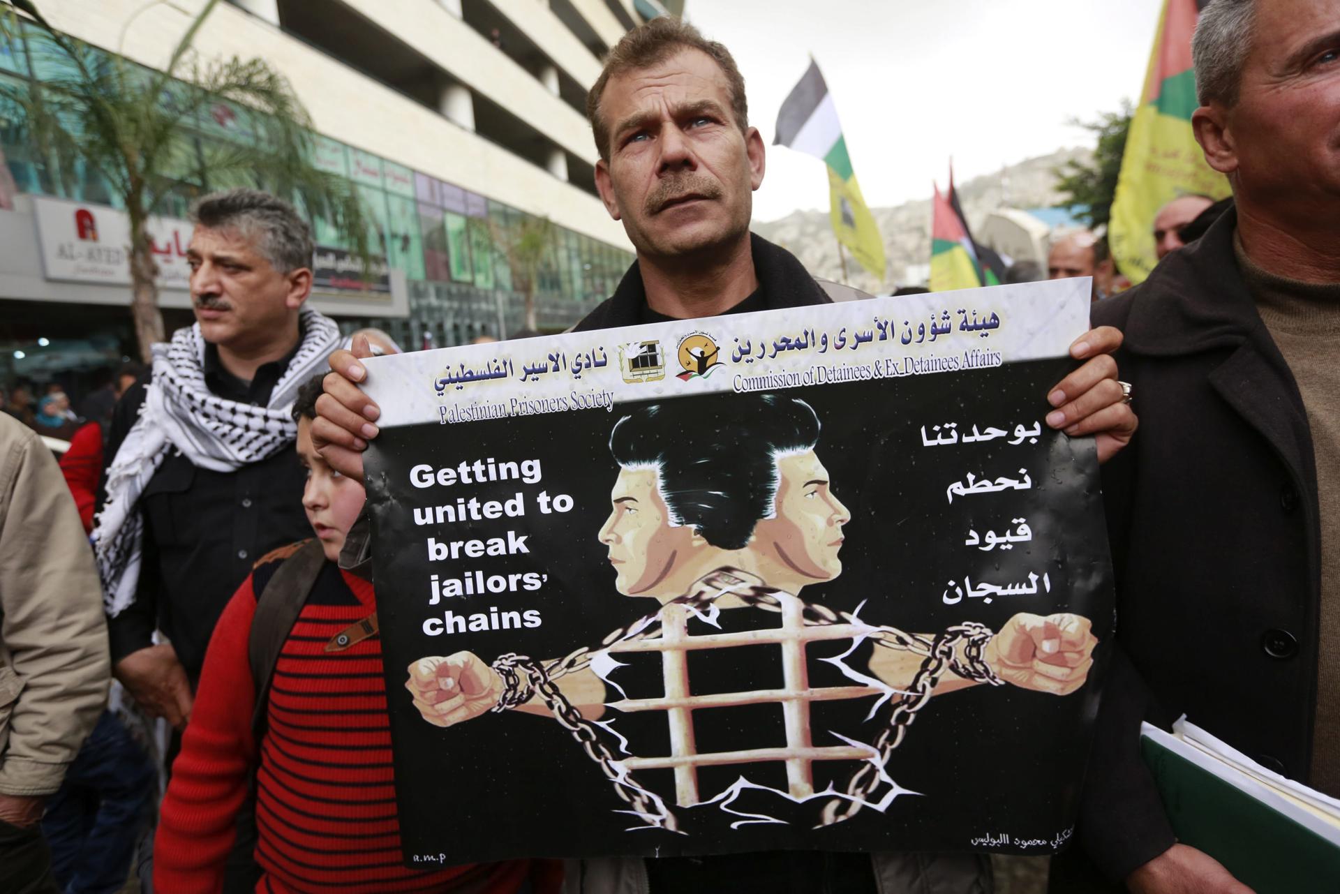 Imagen de archivo de un hombre palestino con un cartel en el que se lee "Unidos para romper las cadenas de la cárcel" durante una protesta para pedir la liberación de sus familiares encarcelados en centros penitenciarios israelíes. EFE/Alaa Badarneh