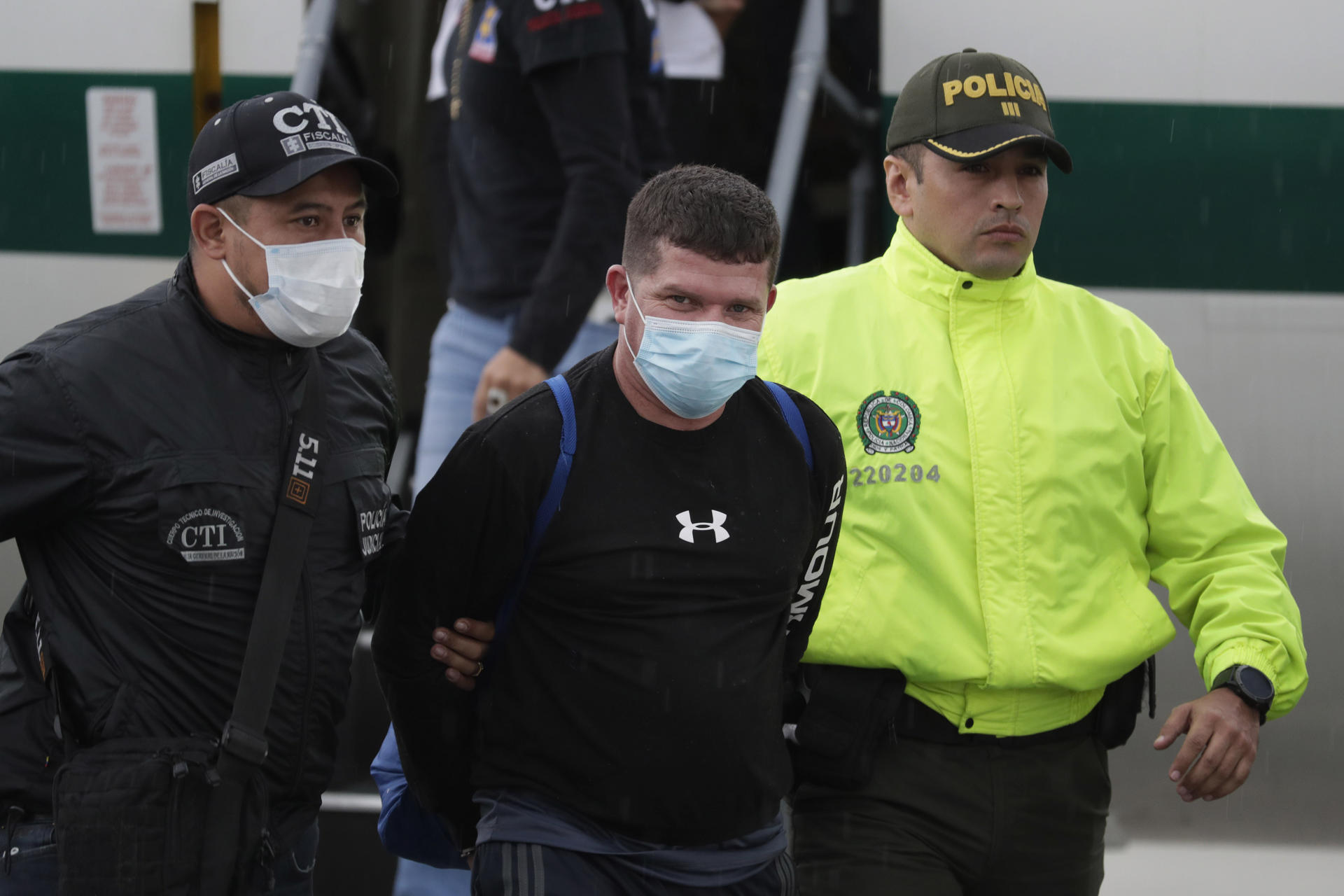 Fotografía del 8 de junio de 2022 en donde se ve a Francisco Luis Correa Galeano (c), capturado por el crimen del fiscal paraguayo Marcelo Pecci, mientras es trasladado por agentes de la Policía y del Cuerpo Técnico de Investigación (CTI) en el Comando Aéreo de Transporte Militar (CATAM) hacia el Bunker de la Fiscalía General de la Nación, en Bogotá (Colombia). EFE/ Carlos Ortega