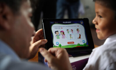 Fotografía de una persona junto a un niño manipulando una tableta en un colegio. EFE/ Paolo Aguilar