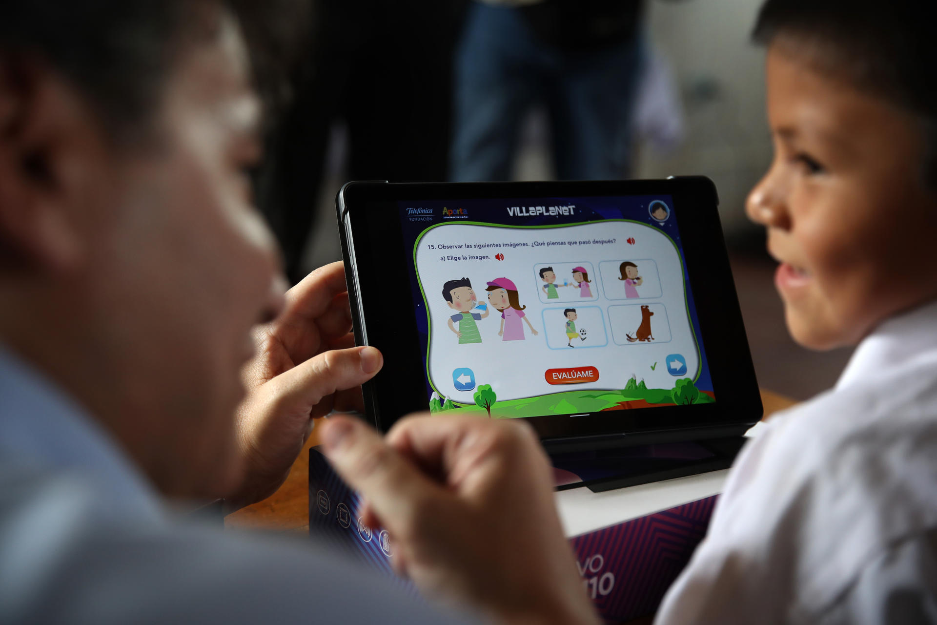 Fotografía de una persona junto a un niño manipulando una tableta en un colegio. EFE/ Paolo Aguilar