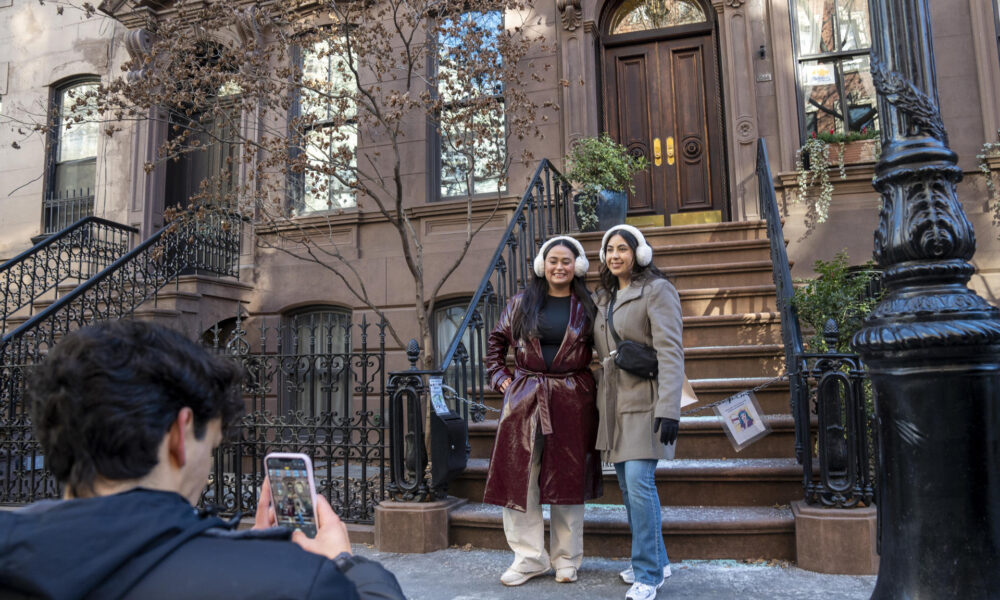 Una pareja de turistas se toma fotos este martes, frente a la casa donde se grabó la serie Sex and the City, en Nueva York (EE.UU.). EFE/ Ángel Colmenares