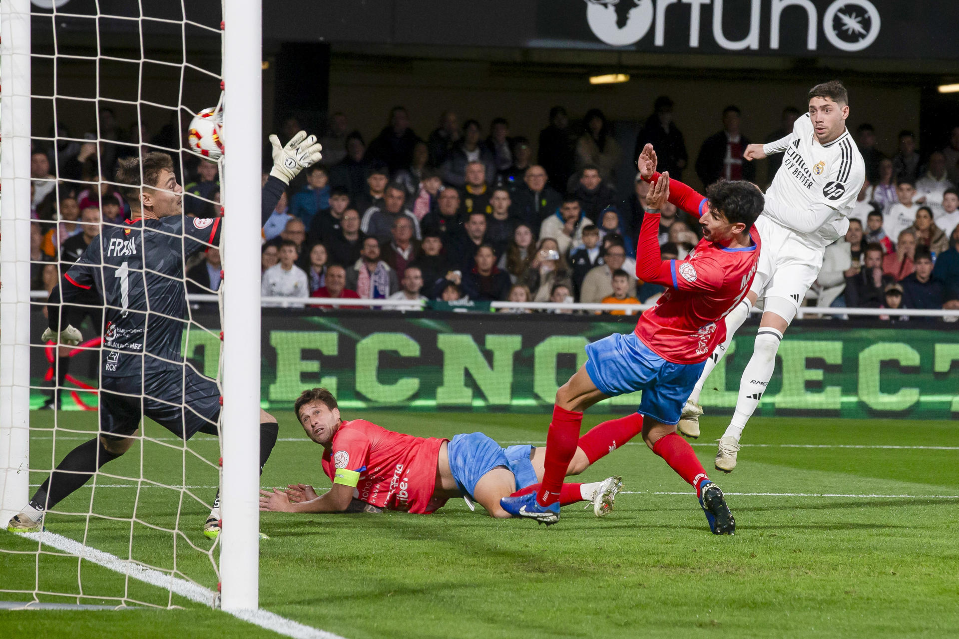 El centrocampista uruguayo del Real Madrid Fede Valverde (d) dispara en la jugada del primer gol ante de la Deportiva Minera durante el partido correspondiente a los dieciseisavos de final de la Copa del Rey, que están disputando este lunes en el estadio Cartagonova en Cartagena. EFE/Marcial Guillén