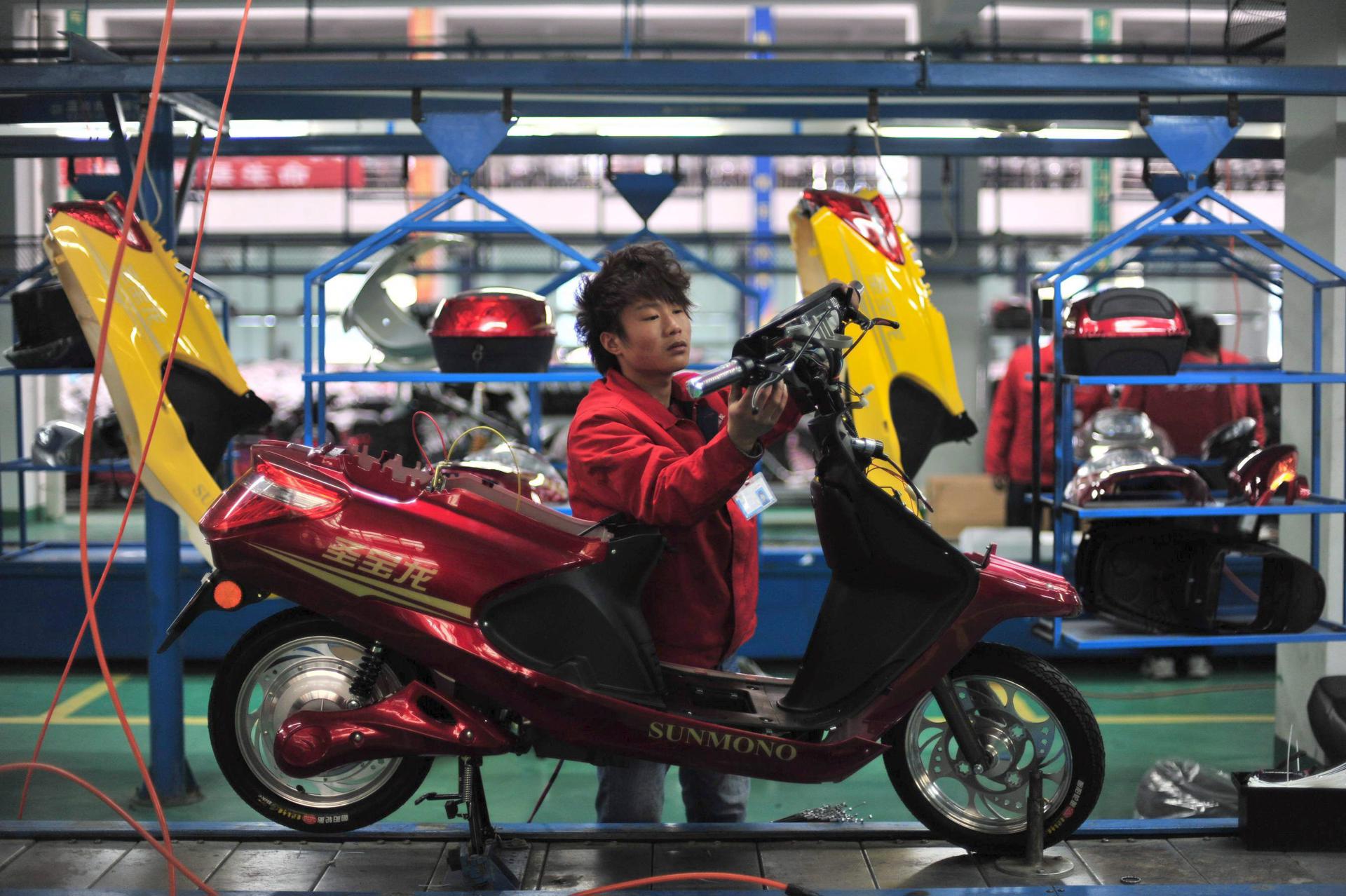 Un trabajador coloca una pieza en una fábrica de motos en Wuhan, China. EFE/SHEPHERD ZHOU