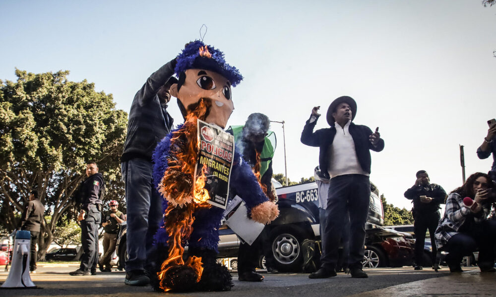 Imagen de archivo de activistas promigrantes de la ciudad mexicana de Tijuana, fronteriza con Estados Unidos, que llevaron a cabo la quema de una piñata de cartón, con la figura de un policía municipal, a manera de protesta por los abusos y delitos que los agentes de la corporación de seguridad cometen en contra de la población migrante. EFE/Joebeth Terriquez