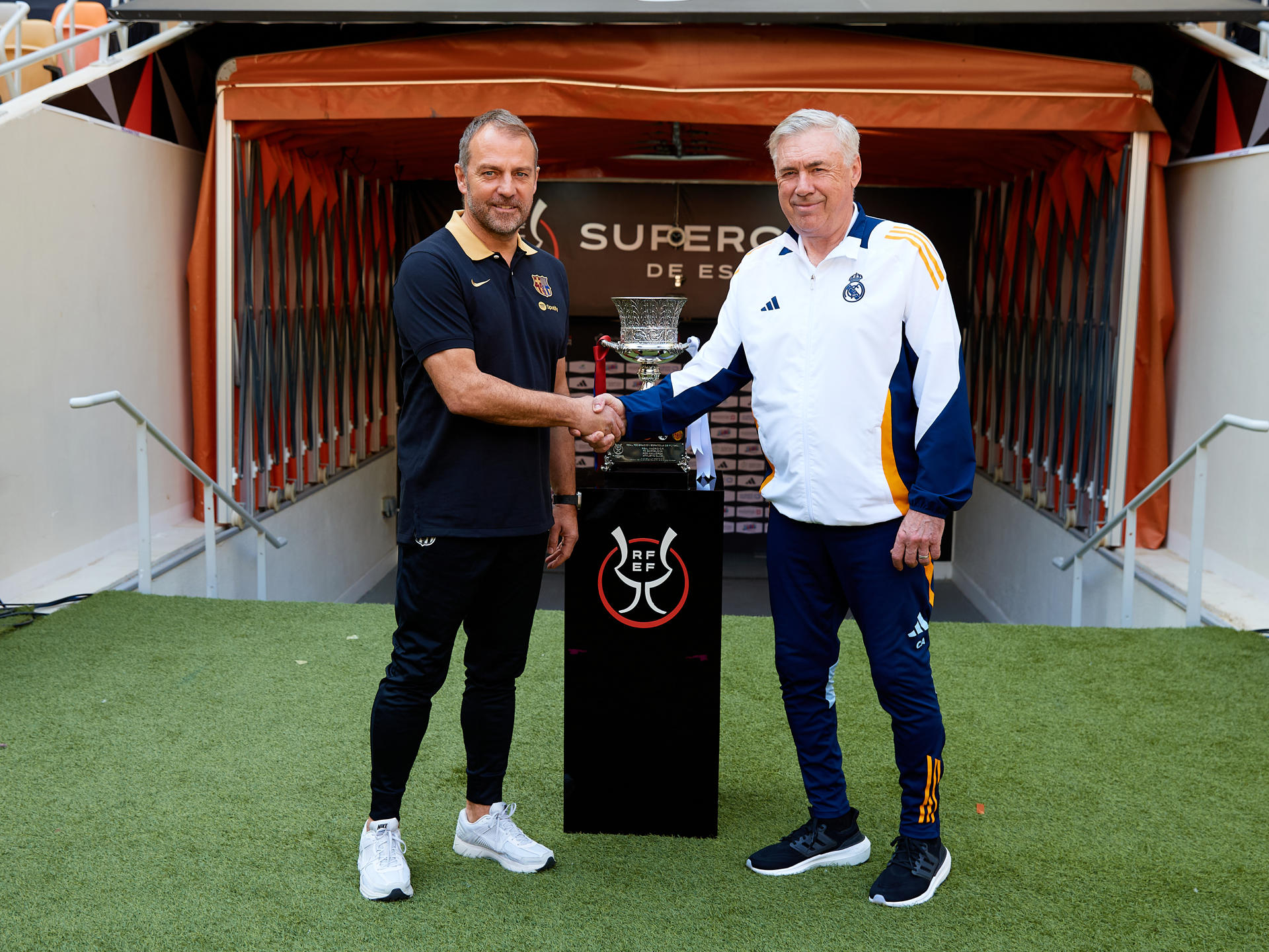 Los entrenadores del Real Madrid CF y el FC Barcelona, Carlo Ancelotti (d) y Hansi Flick (i), respectivamente, han posado este sábado junto al trofeo en el estadio Al Jawhara de Yeda, que mañana acogerá la final de la Supercopa de España. EFE/RFEF/David Aliaga -SOLO USO EDITORIAL/SOLO DISPONIBLE PARA ILUSTRAR LA NOTICIA QUE ACOMPAÑA (CRÉDITO OBLIGATORIO)-