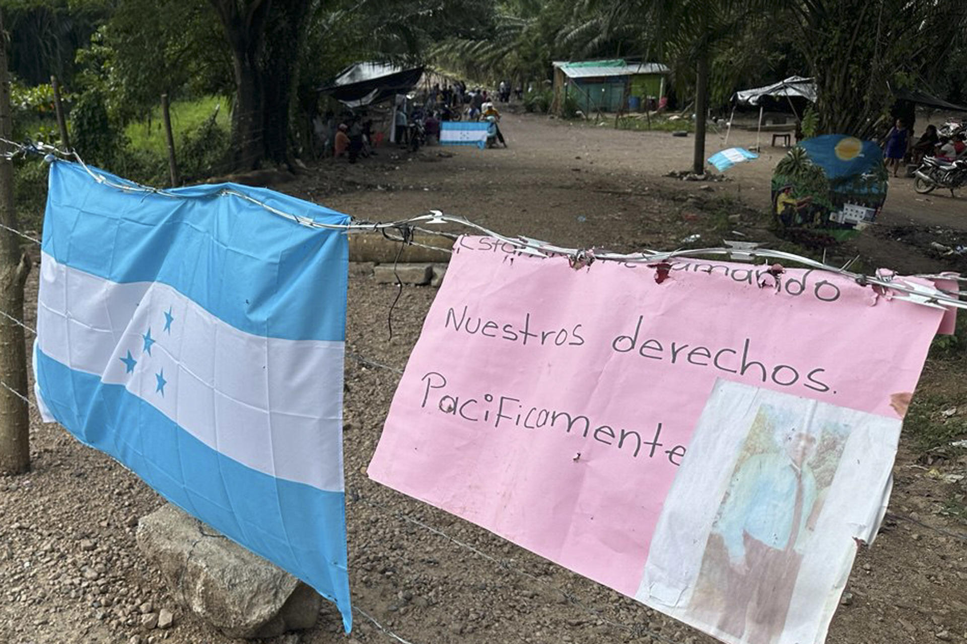 Fotografía del 12 de enero de 2025 de una bandera de Honduras y un cartel durante un plantón de campesinos en Quebrada de Arena (Honduras). EFE/ Germán Reyes