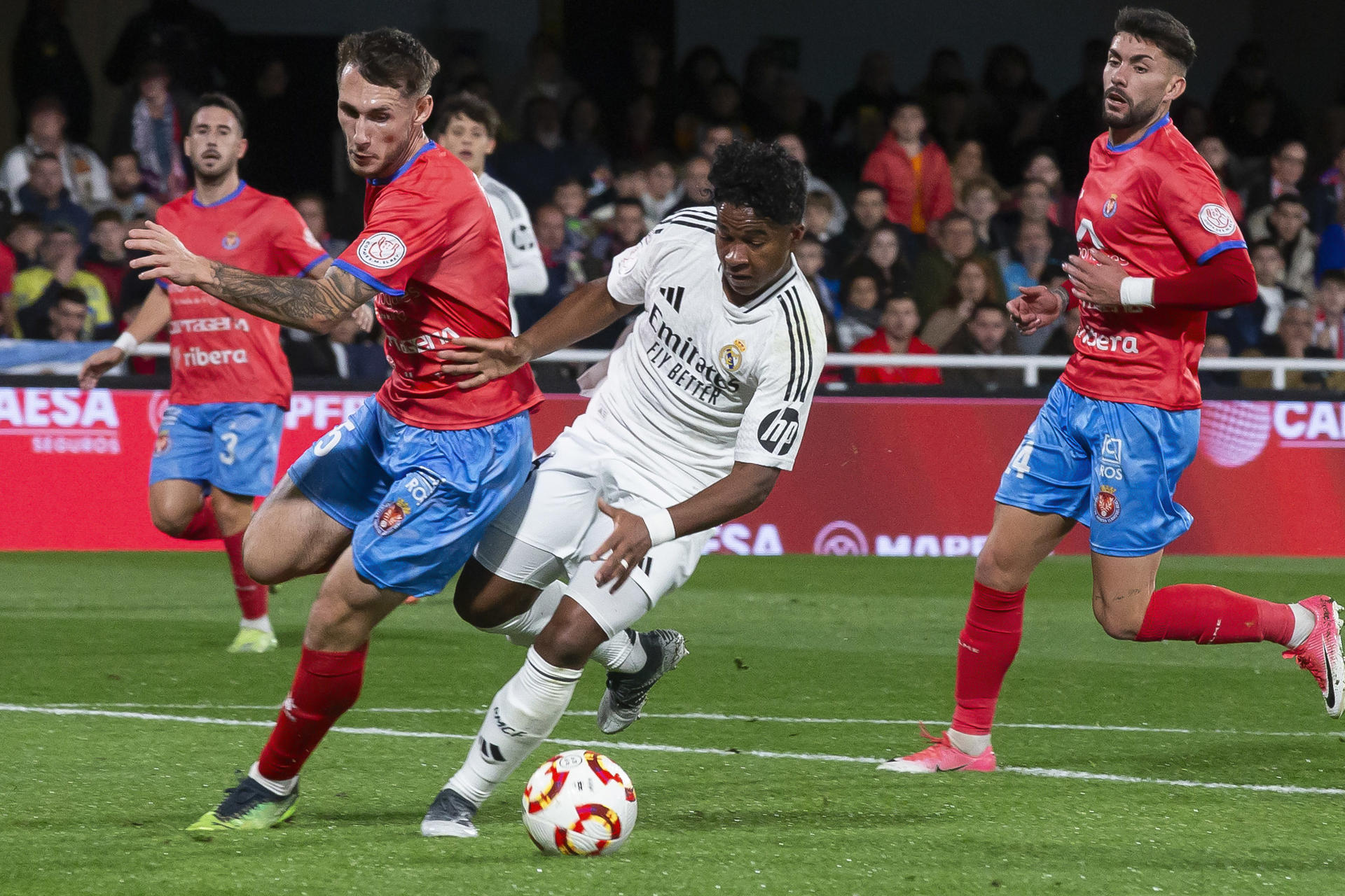 El delantero brasileño del Real Madrid Endrick (c) controla el balón ante el jugador de la Deportiva Minera Fran Molina (2i) durante el partido correspondiente a los dieciseisavos de final de la Copa del Rey, que están disputando este lunes en el estadio Cartagonova en Cartagena. EFE/Marcial Guillén