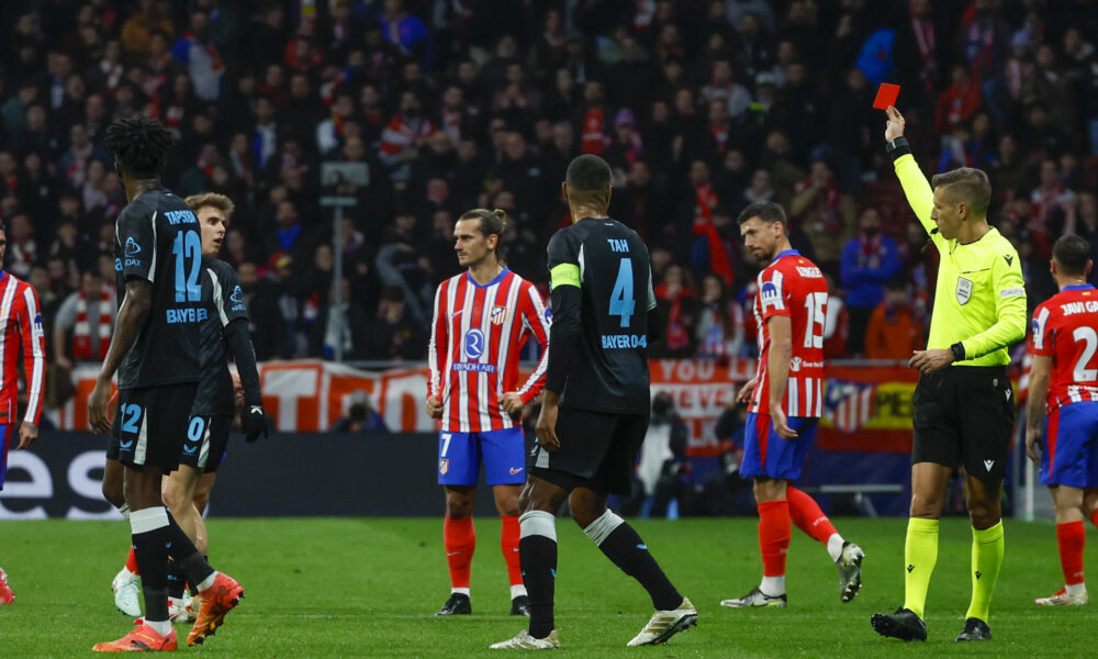 El colegiado muestra tarjeta roja al centrocampista del Atlético de Madrid, Pablo Barrios (2i), durante el encuentro correspondiente a la fase regular de la Liga de Campeones que disputan hoy martes Atlético de Madrid y Bayer Leverkusen en el estadio Metropolitano, en Madrid. EFE / Juanjo Martín.