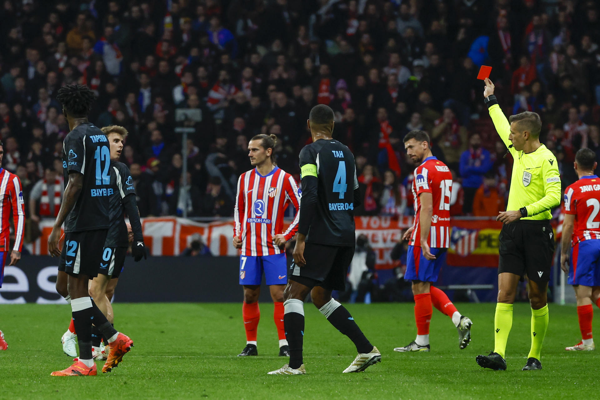 El colegiado muestra tarjeta roja al centrocampista del Atlético de Madrid, Pablo Barrios (2i), durante el encuentro correspondiente a la fase regular de la Liga de Campeones que disputan hoy martes Atlético de Madrid y Bayer Leverkusen en el estadio Metropolitano, en Madrid. EFE / Juanjo Martín.