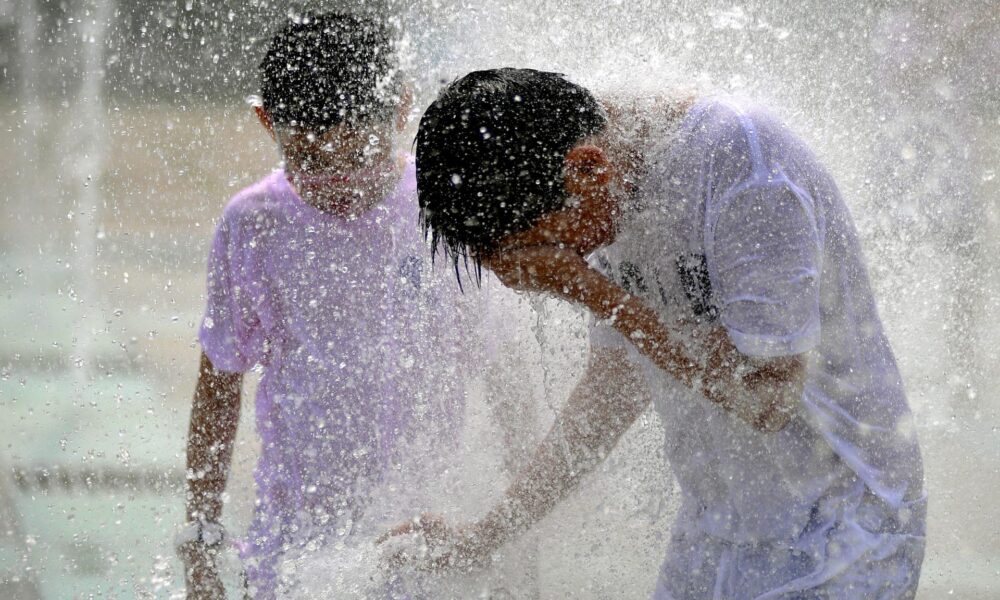 Dos jóvenes se refrescan en una fuente en Qingdao, en la provincia de Shandong (China), en una fotografía de archivo. EFE/Wu Hong