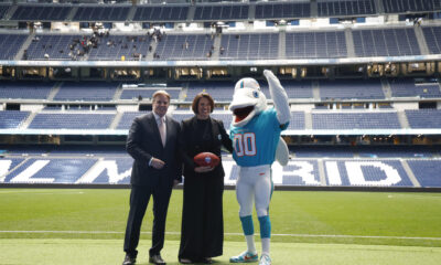 Brett Gosper, director de la NFL en Europa y Asia-Pacífico y Pri Shumate, vicepresidenta de los Miami Dolphins, en el césped del Santiago Bernabéu con la mascota del equipo, durante el acto celebrado este viernes. EFE/ Blanca Millez