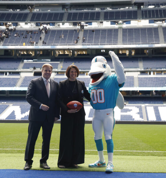 Brett Gosper, director de la NFL en Europa y Asia-Pacífico y Pri Shumate, vicepresidenta de los Miami Dolphins, en el césped del Santiago Bernabéu con la mascota del equipo, durante el acto celebrado este viernes. EFE/ Blanca Millez