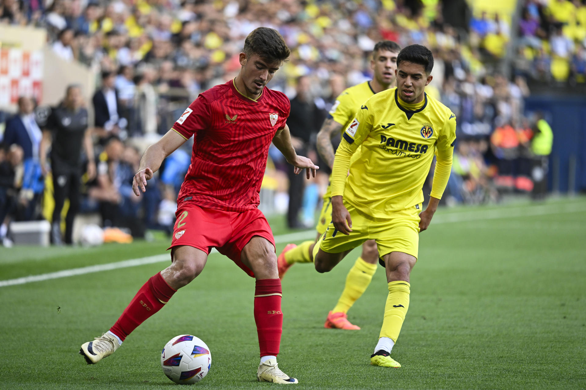 El defensa del Sevilla Kike Salas (i) pelea un balón con el centrocampista del Villarreal Ilias Chakkour (d) durante el partido de la trigésima quinta jornada de la pasada Liga. EFE/ Andreu Esteban