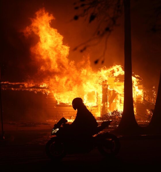 Una persona conduce su motocicleta junto a una casa en llamas durante los incendios en Palisades , California, Estados Unidos. EFE/ Allison Dinner