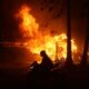 Una persona conduce su motocicleta junto a una casa en llamas durante los incendios en Palisades , California, Estados Unidos. EFE/ Allison Dinner