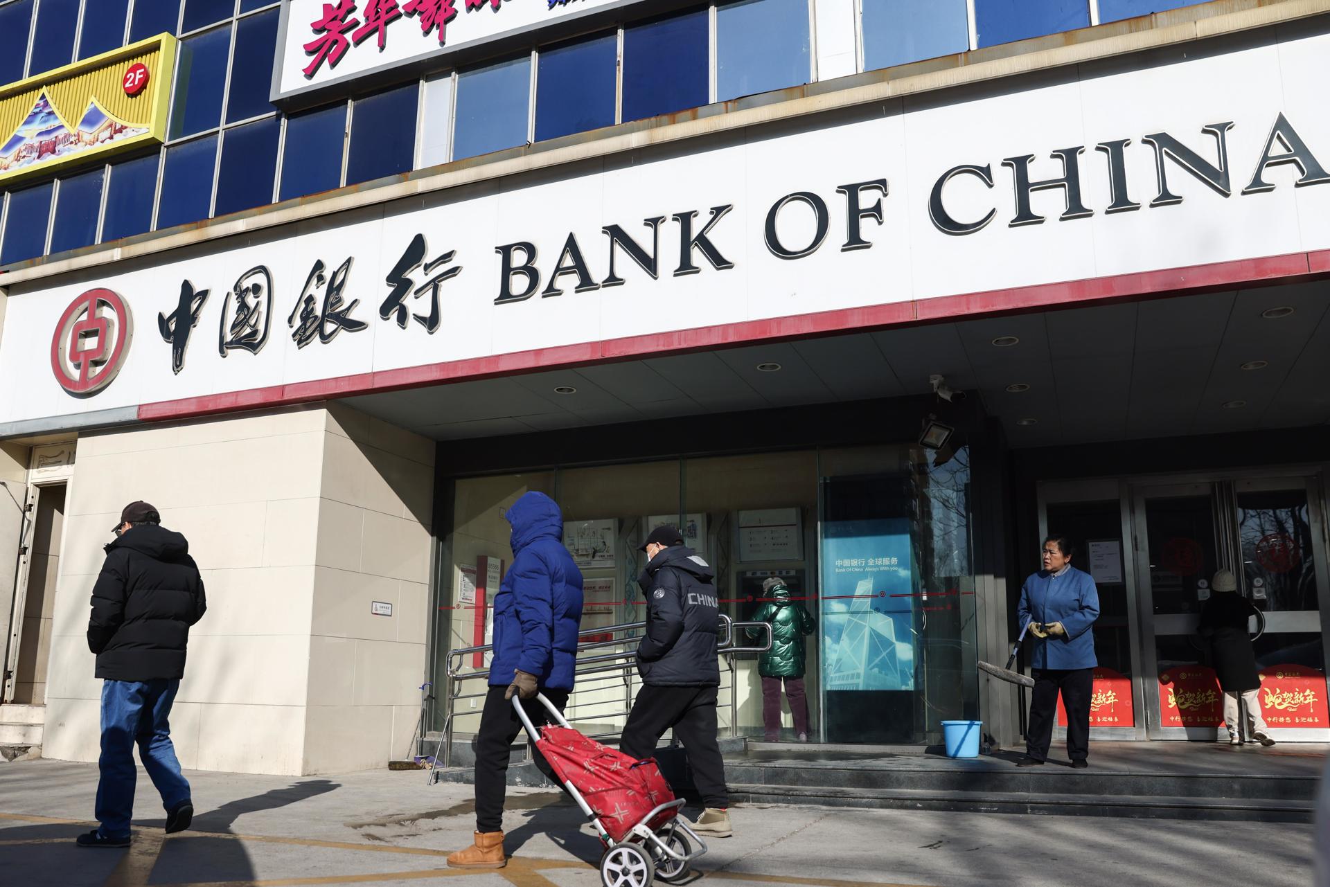 Transeúntes frente a un banco en Beijing, China, el 20 de enero de 2025. El Banco Popular de China (BPC, banco central) anunció que mantendrá su tipo de interés de referencia en el 3,1 % por cuarto mes consecutivo. EFE/EPA/Wu Hao