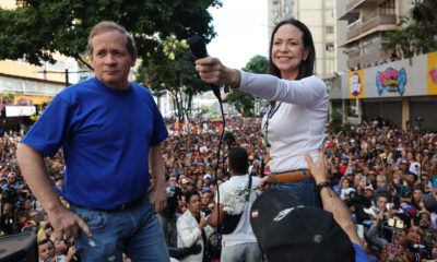 La líder antichavista María Corina Machado (d) saluda a sus seguidores junto al exdiputado venezolano Juan Pablo Guanipa este jueves, en una manifestación en Caracas (Venezuela). EFE/ Miguel Gutiérrez